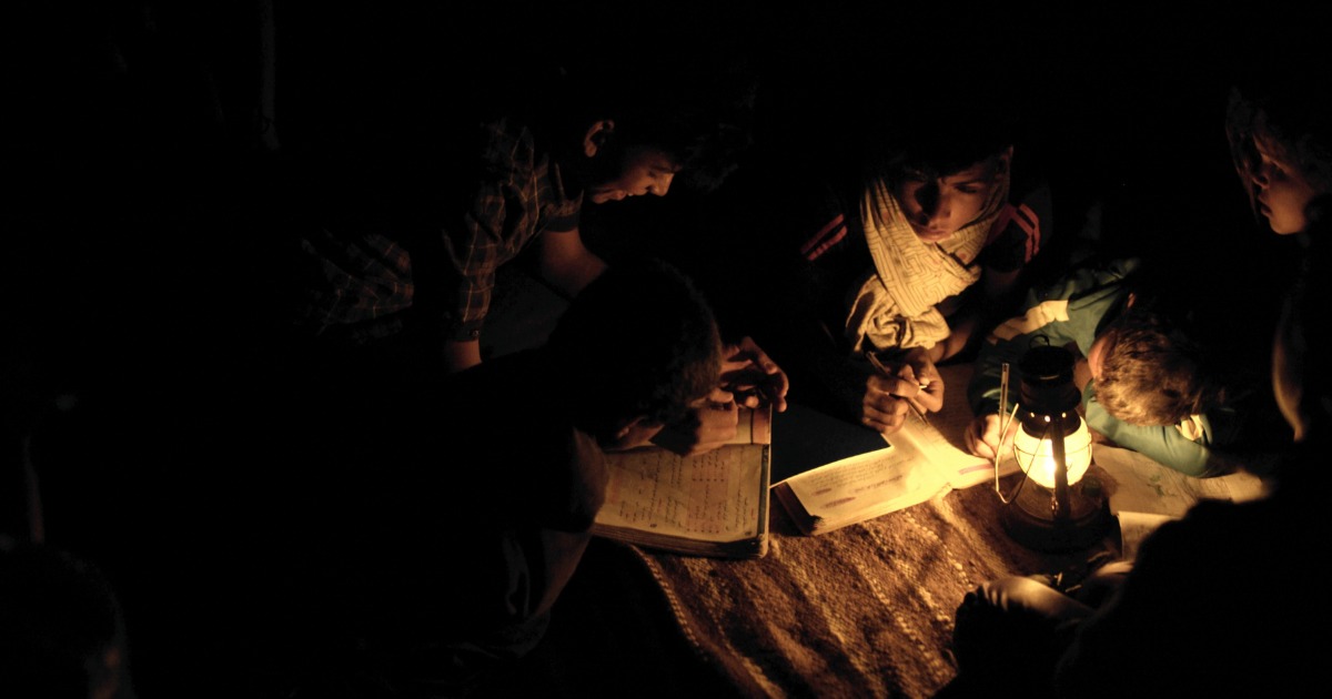 people gathered around a lantern to read