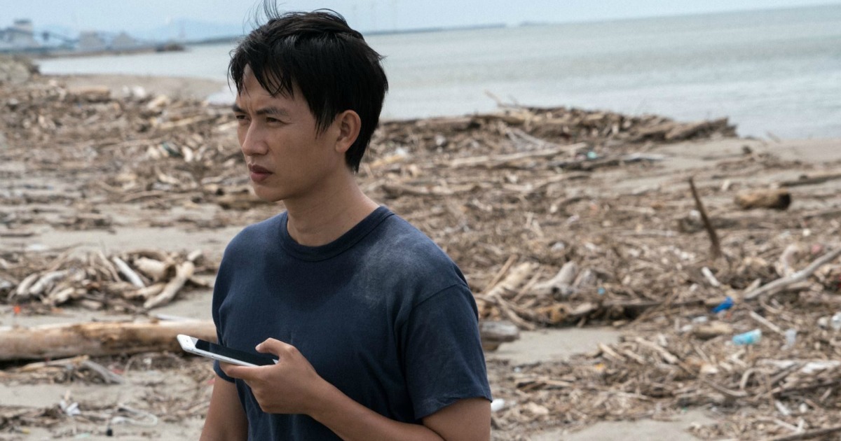 young man with cell phone on beach