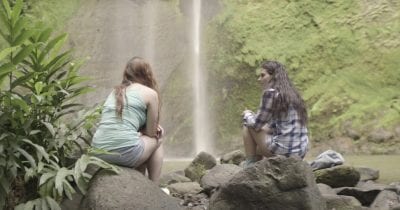 women talking in front of waterfall