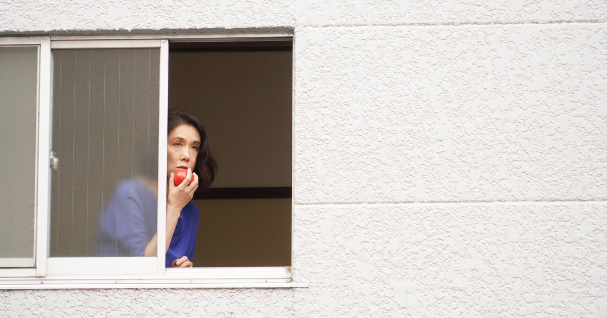 woman looking out window eating apple