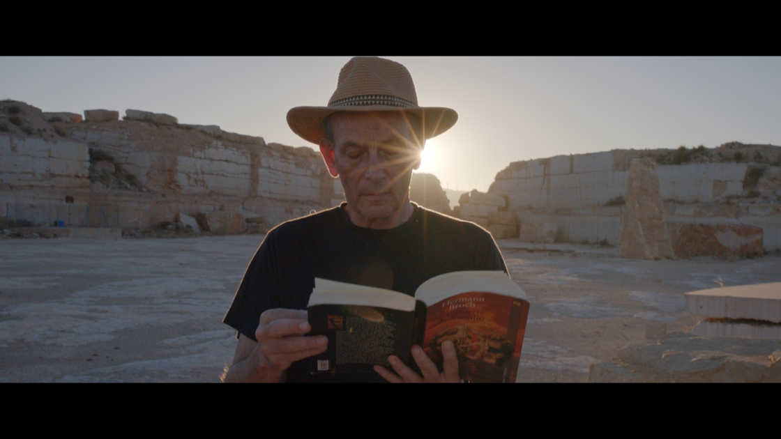 man reading book in desert