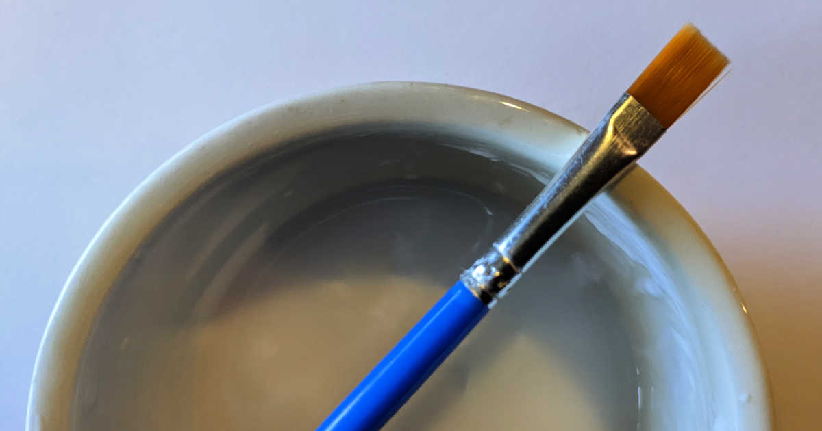 paint brush and bowl filled with thinned glue