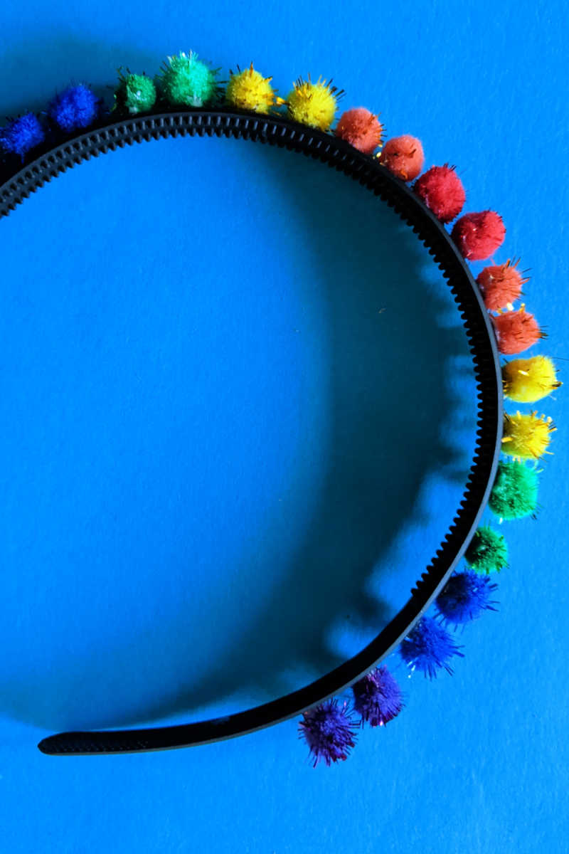 Make an easy rainbow headband craft with colorful pom poms for St. Patrick's Day, Pride or anytime you feel like making a hair accessory.