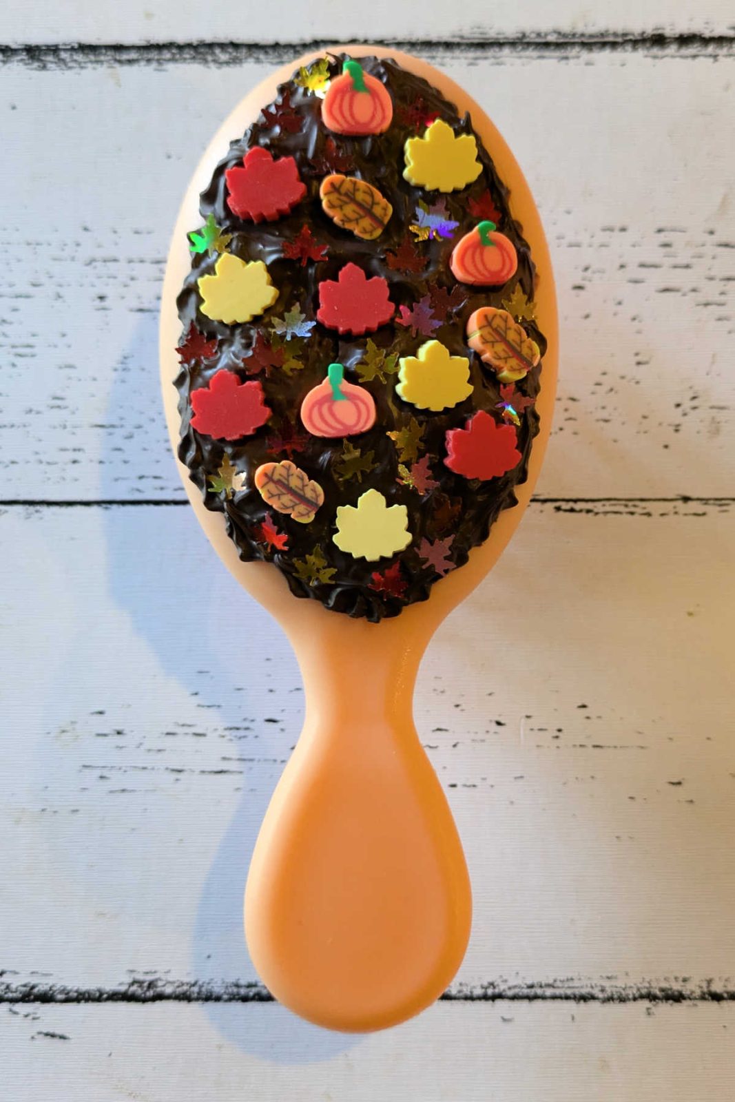 Create a unique and fun fall hair brush with this easy decoden DIY! Use whipped cream glue and fall-themed embellishments to add a touch of autumn to your hair routine.